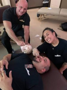 Brandon demoing with a skeleton for students while teaching them TMJ work at Texas Massage Academy